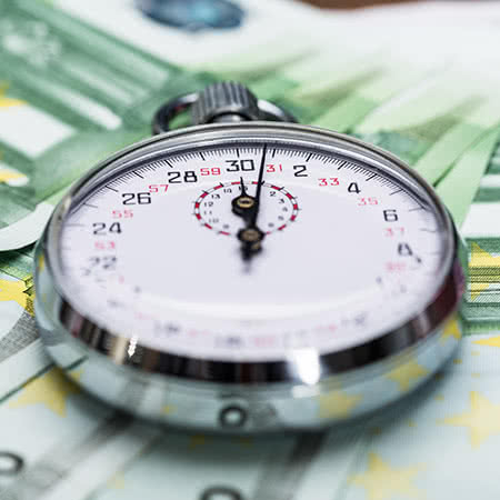 Kreditversicherung - Eine Stoppuhr liegt auf den Geldscheinen